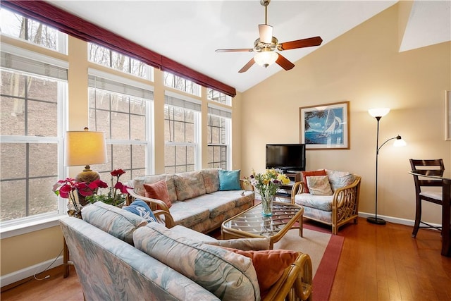 living area with a ceiling fan, baseboards, vaulted ceiling, and hardwood / wood-style flooring