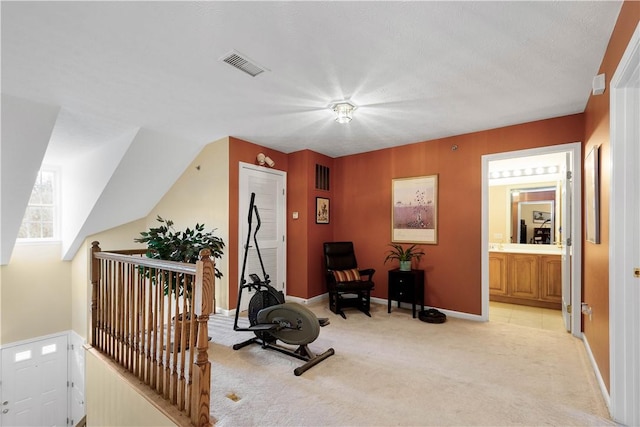 exercise room with visible vents, baseboards, and light carpet