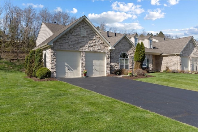 ranch-style house featuring an attached garage, stone siding, a front yard, and driveway