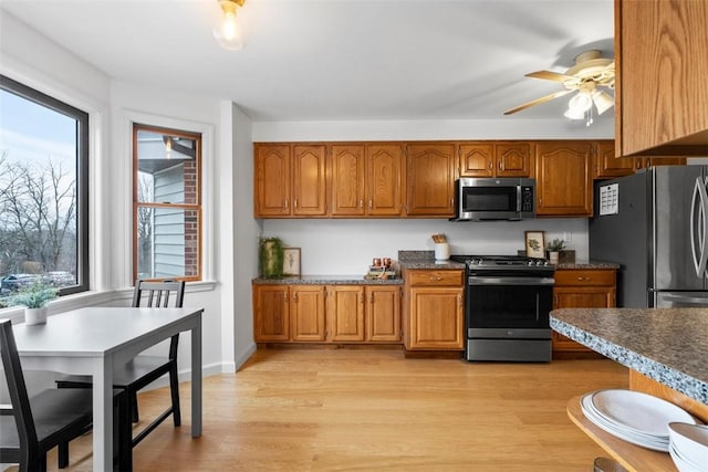 kitchen with baseboards, brown cabinetry, a ceiling fan, appliances with stainless steel finishes, and light wood-style floors