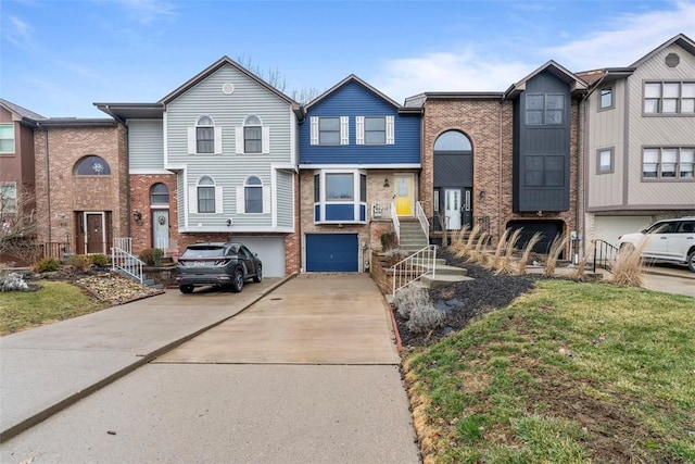 townhome / multi-family property featuring driveway, a garage, and brick siding