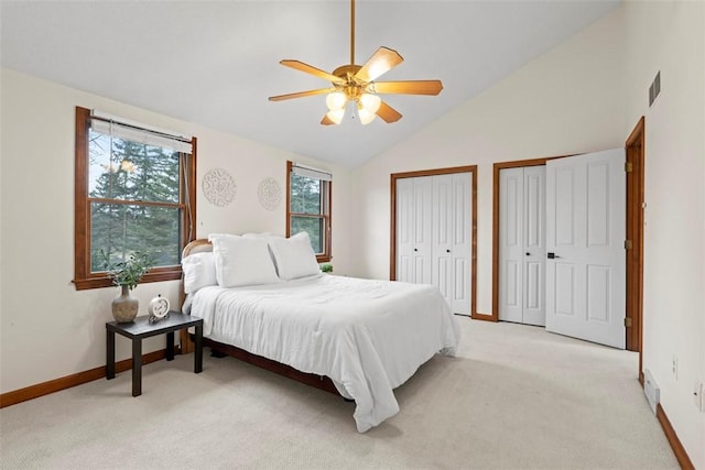 bedroom featuring visible vents, baseboards, a ceiling fan, light colored carpet, and multiple closets