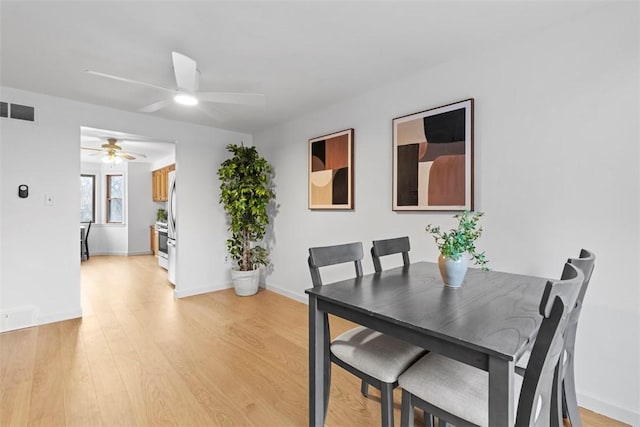 dining room with ceiling fan, light wood-type flooring, visible vents, and baseboards