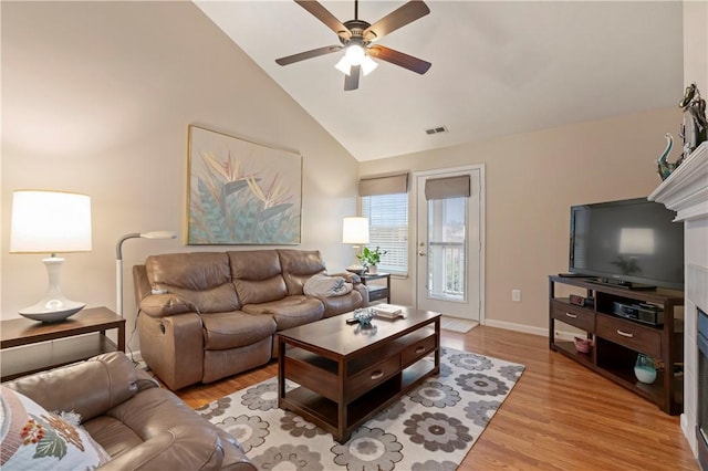 living room with light wood finished floors, visible vents, baseboards, ceiling fan, and high vaulted ceiling