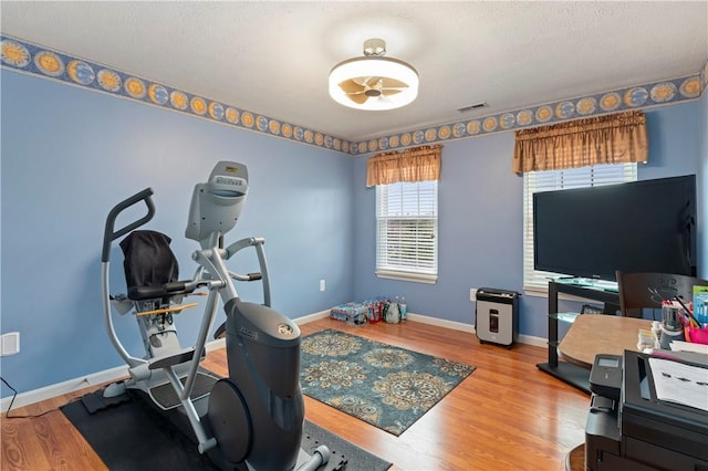 workout room with visible vents, baseboards, and wood finished floors