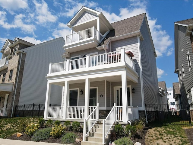 view of front of property with a porch, fence, a balcony, and a shingled roof