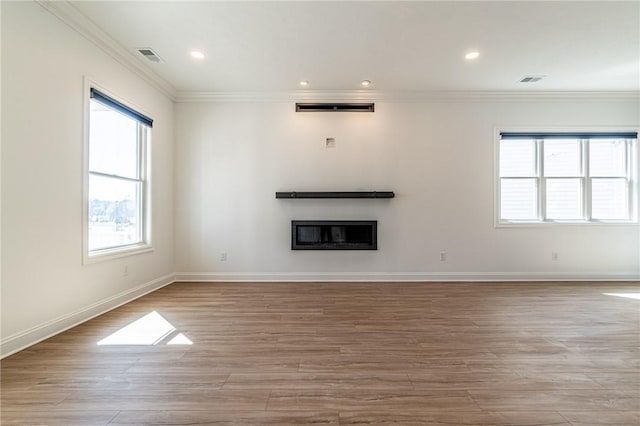 unfurnished living room with recessed lighting, wood finished floors, baseboards, a glass covered fireplace, and crown molding