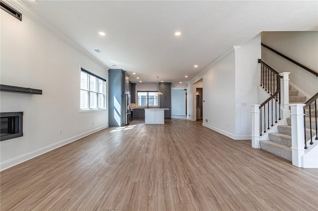 unfurnished living room with baseboards, a glass covered fireplace, light wood-style flooring, stairway, and recessed lighting