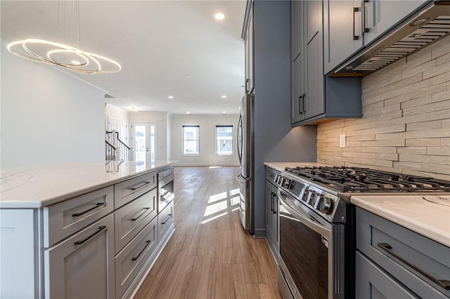 kitchen featuring stainless steel appliances, decorative backsplash, under cabinet range hood, and gray cabinetry