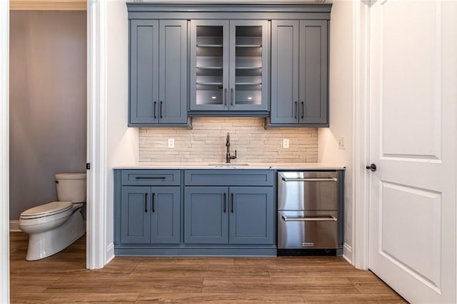 bar with a sink, backsplash, and light wood finished floors