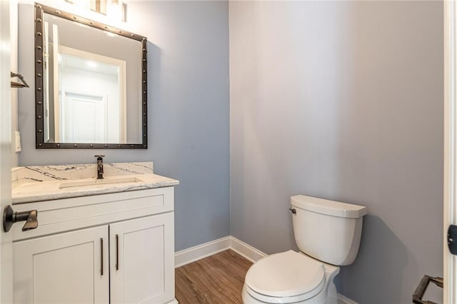 bathroom featuring toilet, vanity, baseboards, and wood finished floors