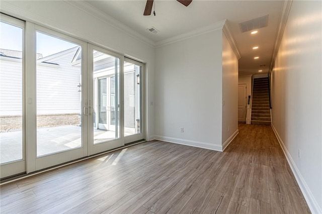 spare room with wood finished floors, visible vents, baseboards, ornamental molding, and stairway