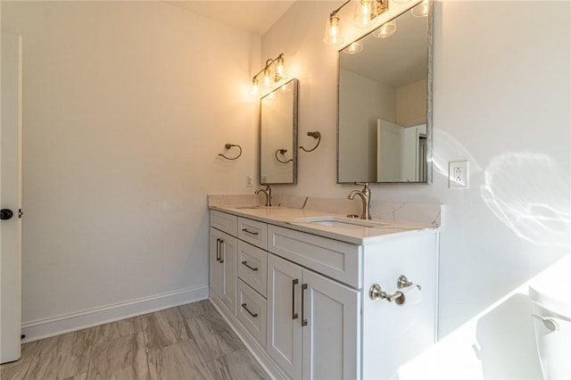 full bath with a sink, baseboards, and double vanity