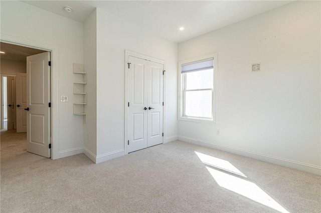 unfurnished bedroom with recessed lighting, a closet, light colored carpet, and baseboards