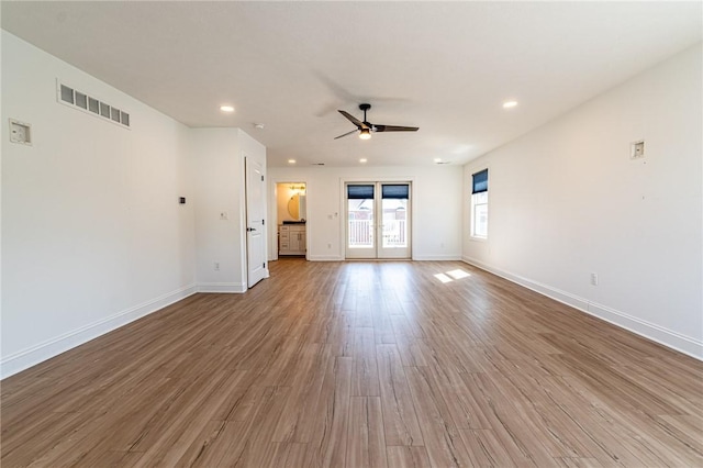 unfurnished living room with french doors, visible vents, baseboards, and wood finished floors