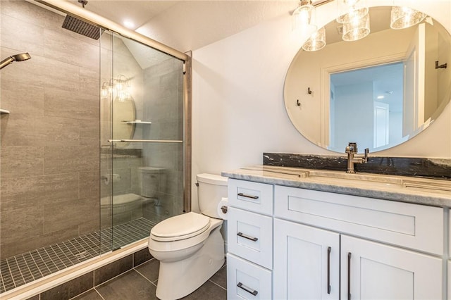 full bath with toilet, a stall shower, vanity, and tile patterned floors