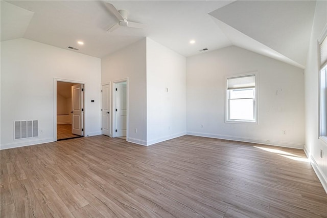 unfurnished room with light wood-type flooring, visible vents, and vaulted ceiling