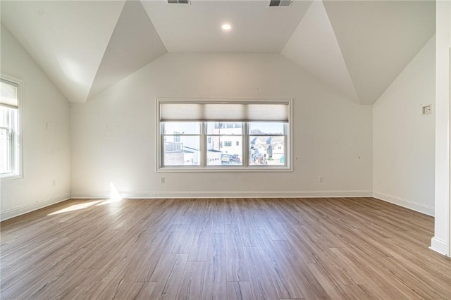 spare room featuring lofted ceiling, plenty of natural light, and wood finished floors