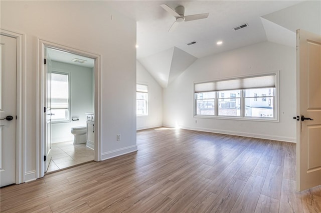 unfurnished room with light wood-style floors, visible vents, and vaulted ceiling