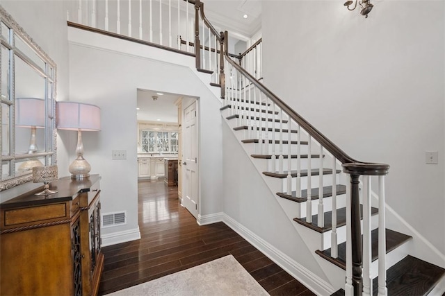 stairs with a high ceiling, a healthy amount of sunlight, baseboards, and wood finished floors