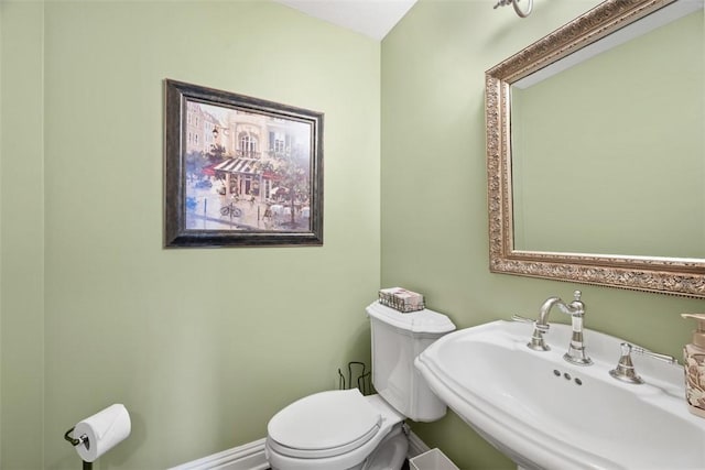 bathroom featuring toilet, baseboards, and a sink