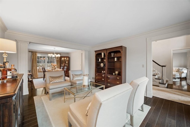 living area featuring ornate columns, stairway, dark wood-style floors, an inviting chandelier, and crown molding