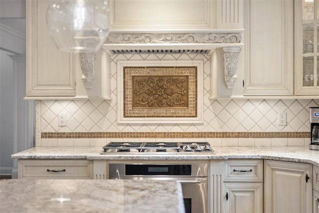 kitchen with appliances with stainless steel finishes, glass insert cabinets, decorative backsplash, and cream cabinets