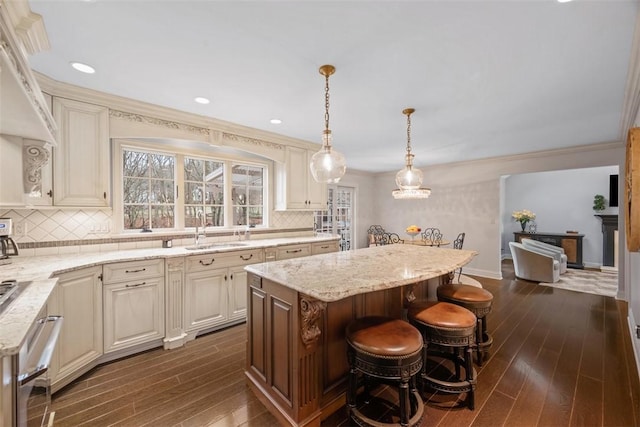 kitchen with light stone counters, a center island, dark wood finished floors, and a sink