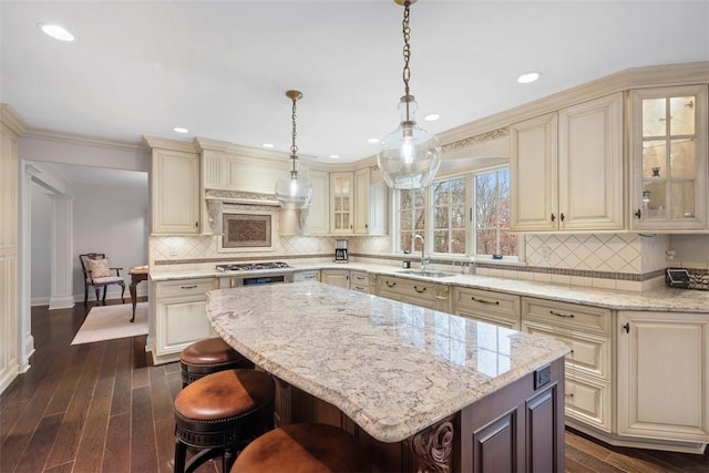 kitchen with a sink, dark wood-style flooring, a breakfast bar, and cream cabinetry