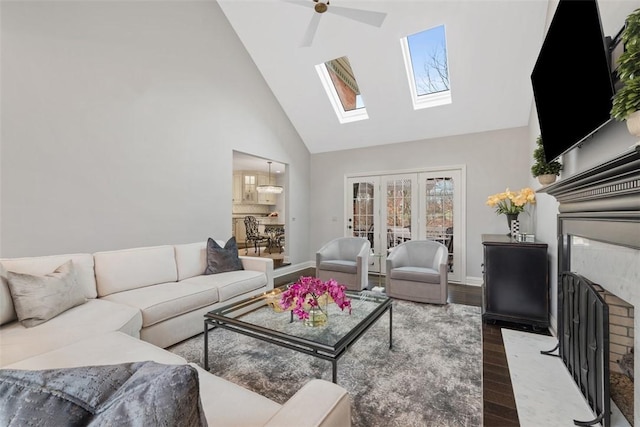 living area featuring a fireplace with flush hearth, ceiling fan, wood finished floors, high vaulted ceiling, and baseboards