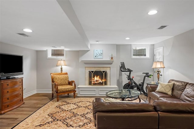 living room featuring a fireplace, visible vents, wood finished floors, and recessed lighting