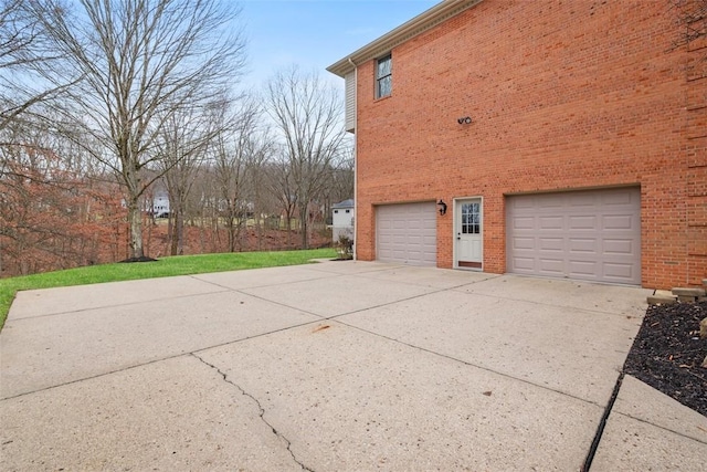 view of side of property with driveway, an attached garage, and brick siding