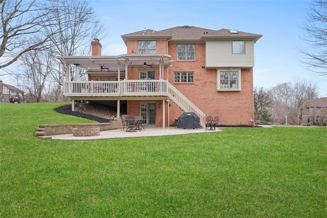 back of house with a yard, brick siding, a deck, and a patio