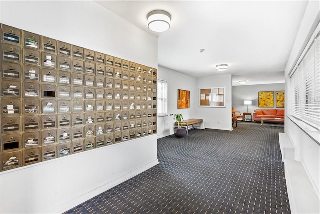 hallway featuring mail area, baseboards, and carpet flooring