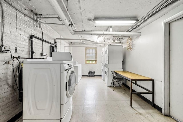 laundry room with brick wall, washing machine and dryer, and baseboards