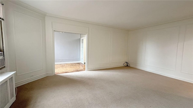 unfurnished room with ornamental molding, carpet flooring, and a decorative wall