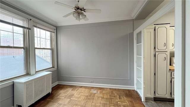 unfurnished room featuring ornamental molding, radiator heating unit, a ceiling fan, and baseboards