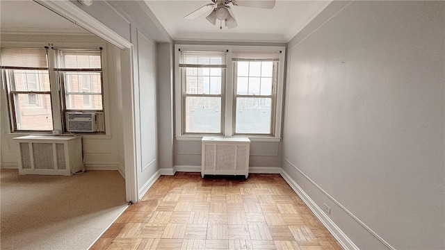 spare room featuring cooling unit, a ceiling fan, baseboards, radiator, and crown molding