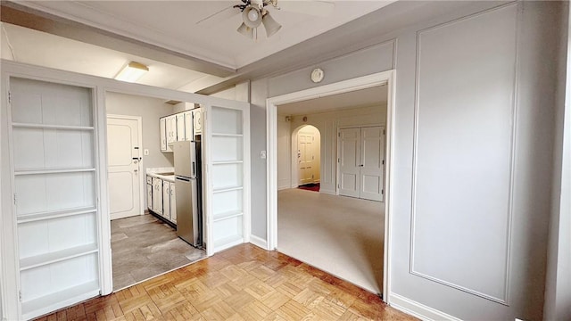 interior space with arched walkways, white cabinetry, a ceiling fan, light countertops, and freestanding refrigerator