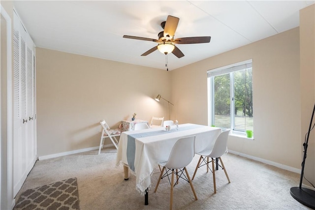 dining room with light carpet, ceiling fan, and baseboards