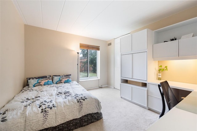 bedroom featuring visible vents, light colored carpet, and built in study area