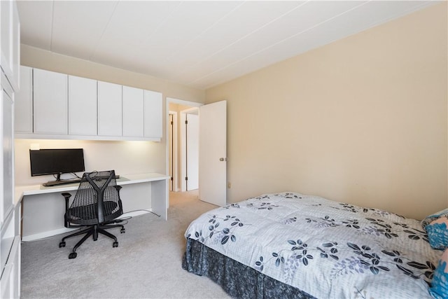 bedroom featuring light carpet and built in study area