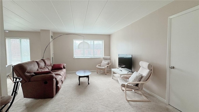 carpeted living area with plenty of natural light and baseboards