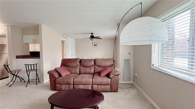 living area featuring light carpet, baseboards, visible vents, and a ceiling fan