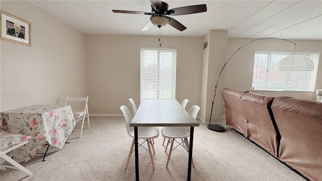 dining room with light colored carpet, ceiling fan, and baseboards