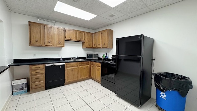 kitchen featuring black appliances, a drop ceiling, dark countertops, and a sink