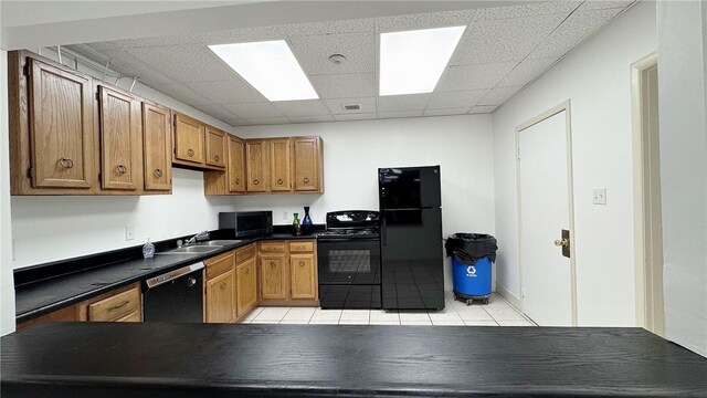 5 Bayard Rd Unit 113, Shadyside, PA 15213 - kitchen featuring light tile patterned floors, a sink, dark countertops, a paneled ceiling, and black appliances