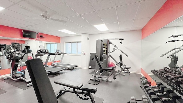 workout area with a paneled ceiling, ceiling fan, and baseboards