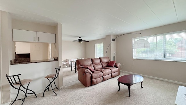 living room featuring light colored carpet, baseboards, and a ceiling fan