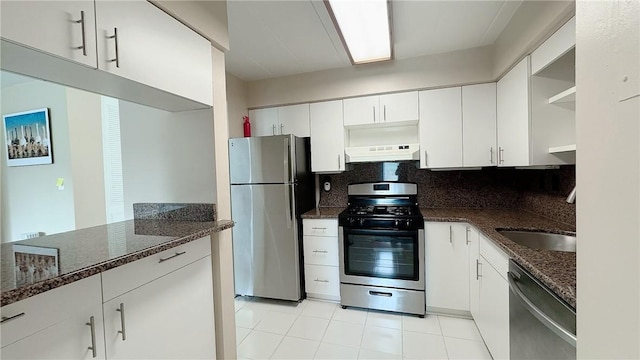 kitchen with under cabinet range hood, open shelves, dark stone countertops, stainless steel appliances, and tasteful backsplash
